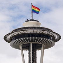 Photo of pride flag flying atop the Seattle Space Needle.