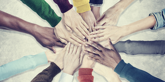 Racial diversity represented in people hands together on top of each other in unity team cooperation concept.