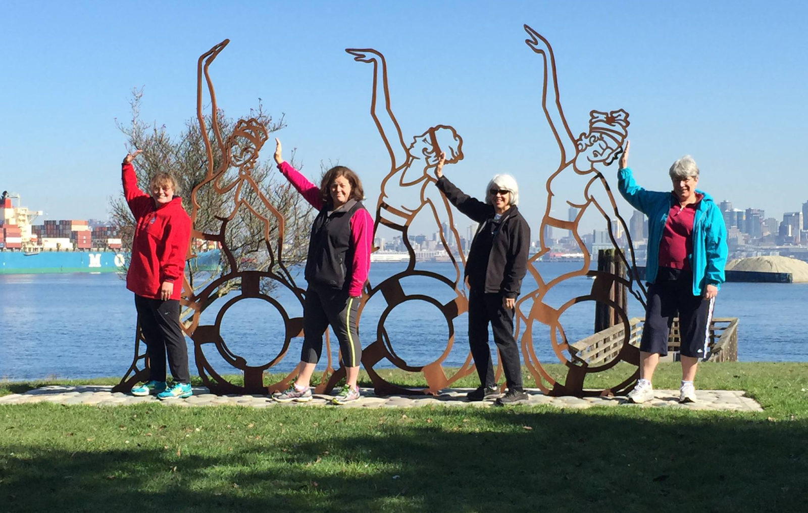 THree women standing next to metal art work of LunaGirls with same pose.