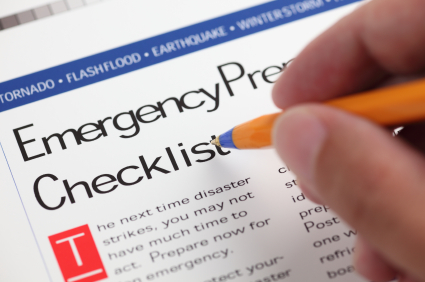 Piece of paper with header that states Emergency Preparedness Checklist with hand holding pencil as if making writing