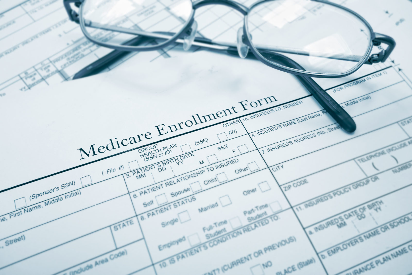 Picture of a Medicare enrollment form with eye glasses resting on top of the form.
