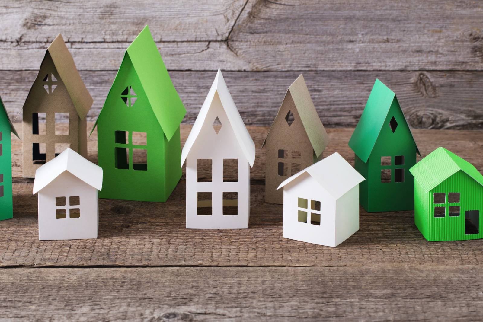 Green white, and brown paper houses on rustic wooden table