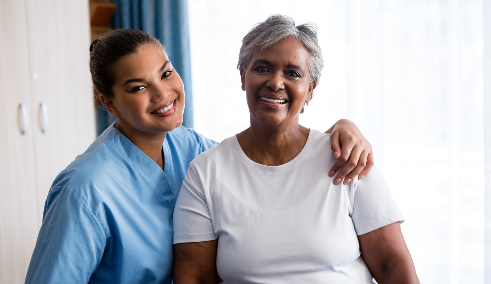 Portrait of young nurse with senior patient in nursing home