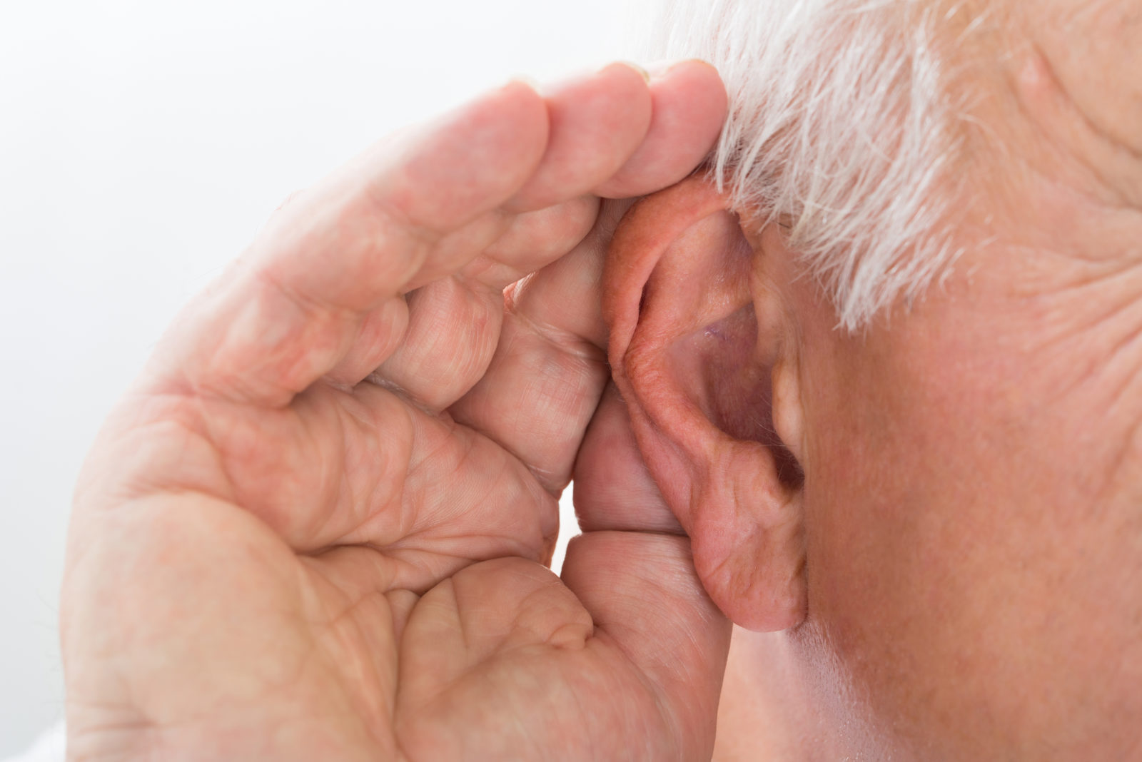 close up image of a man holding his cupped hand to his ear, indicating that he cannot hear well