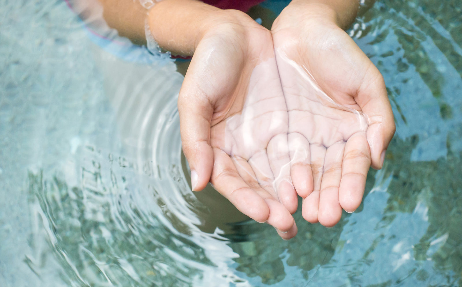 Clear natural water in woman hands.