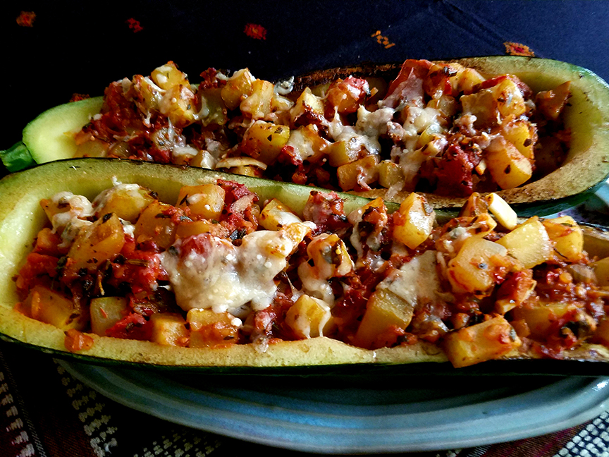Two open-face zucchini halves with stuffing made from diced zucchini, tomatoes, onions, and herbs.