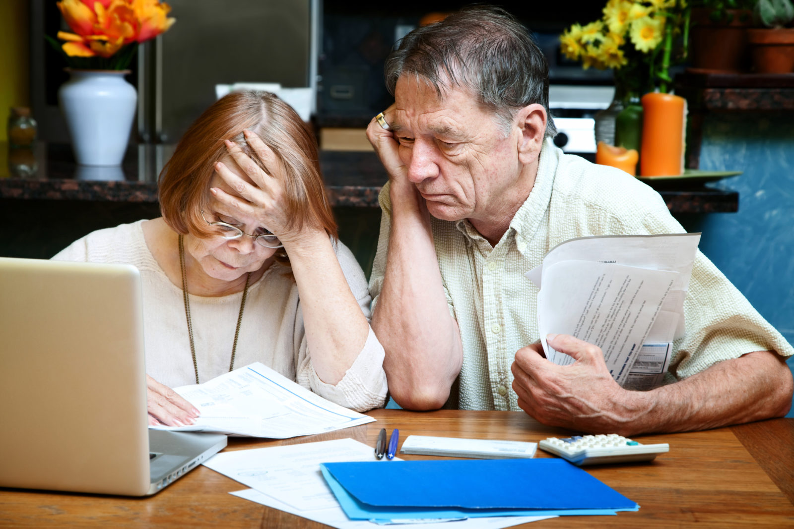Older couple at home reacting to many bills