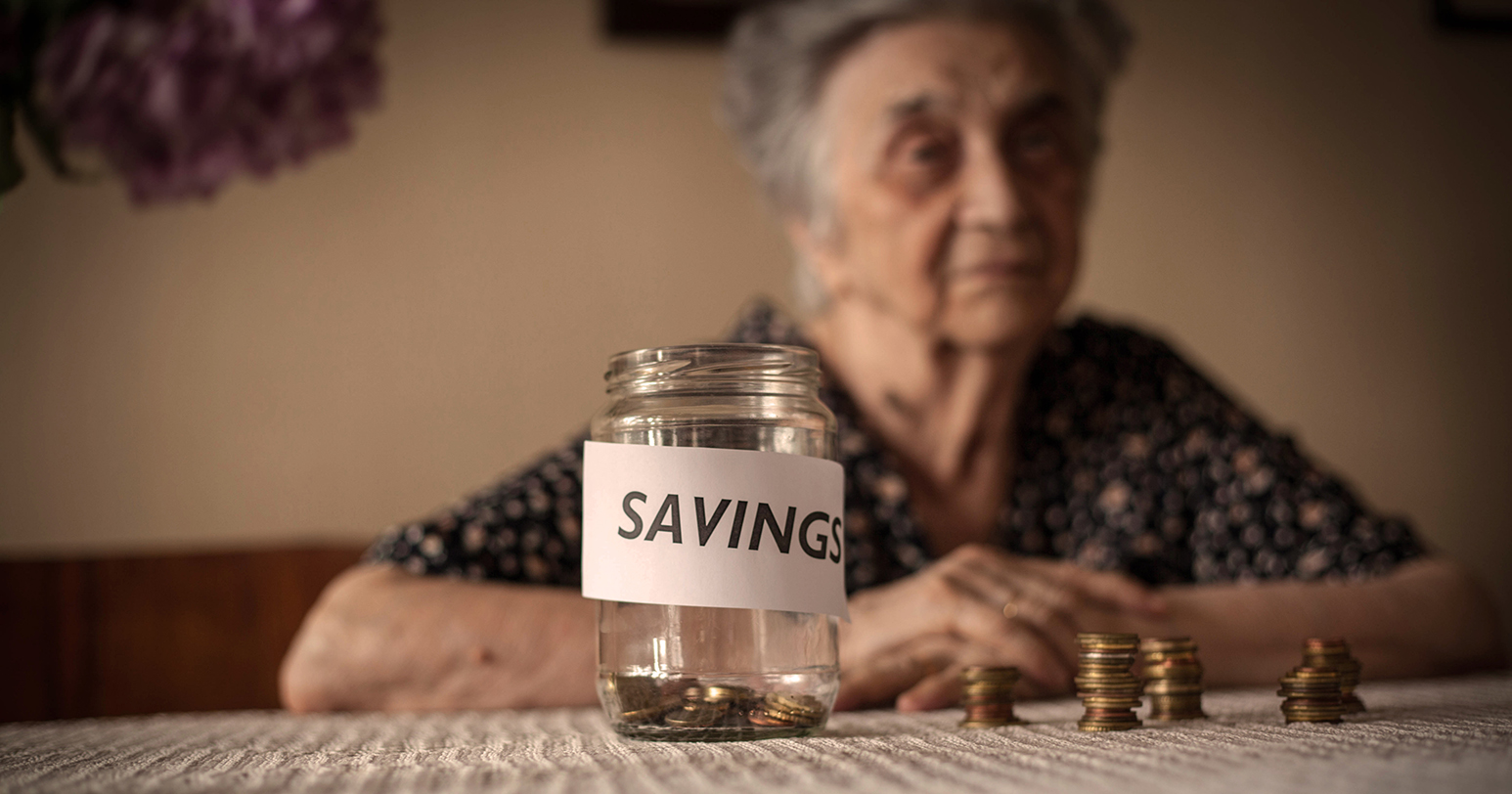 Depressed female pensioner sitting,with her savings jar.