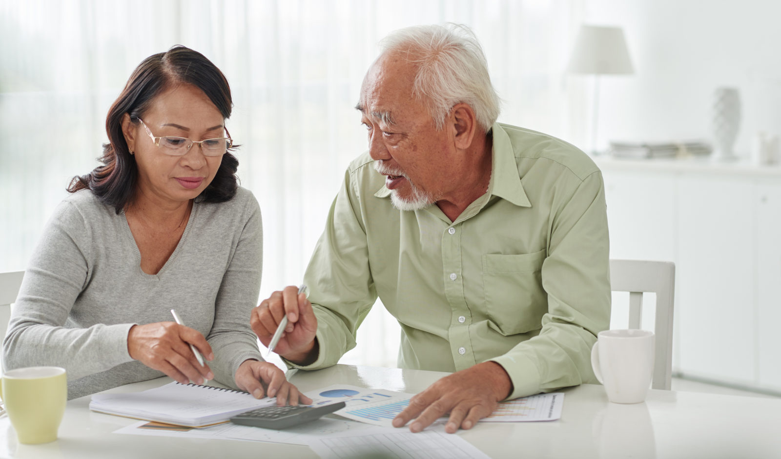 Older Asian woman and man discussing financial documents