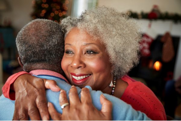 photo of an attractive African American woman with gray hair hugging an African American man