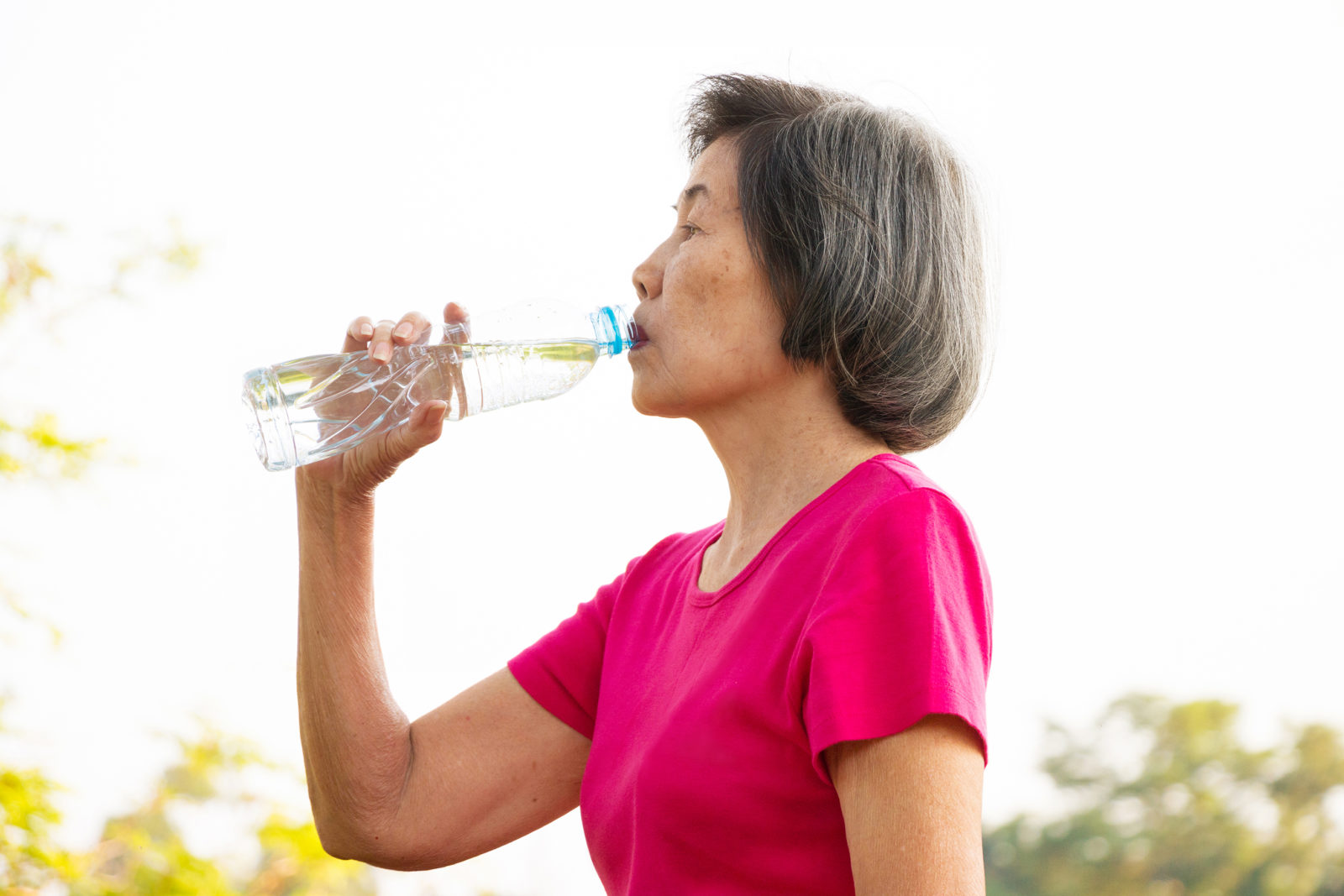 Asian senior woman drinking water from the bottle.