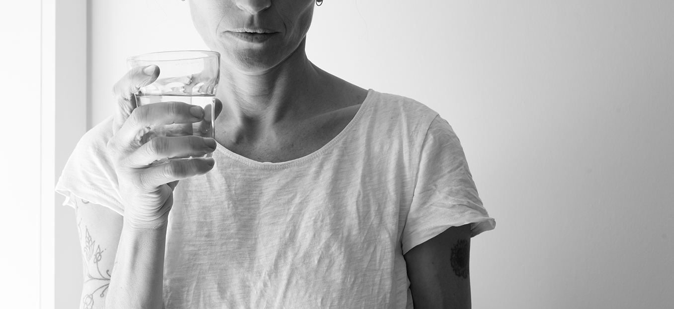 Middle aged woman holding glass and looking pensive - addiction concept (black and white)