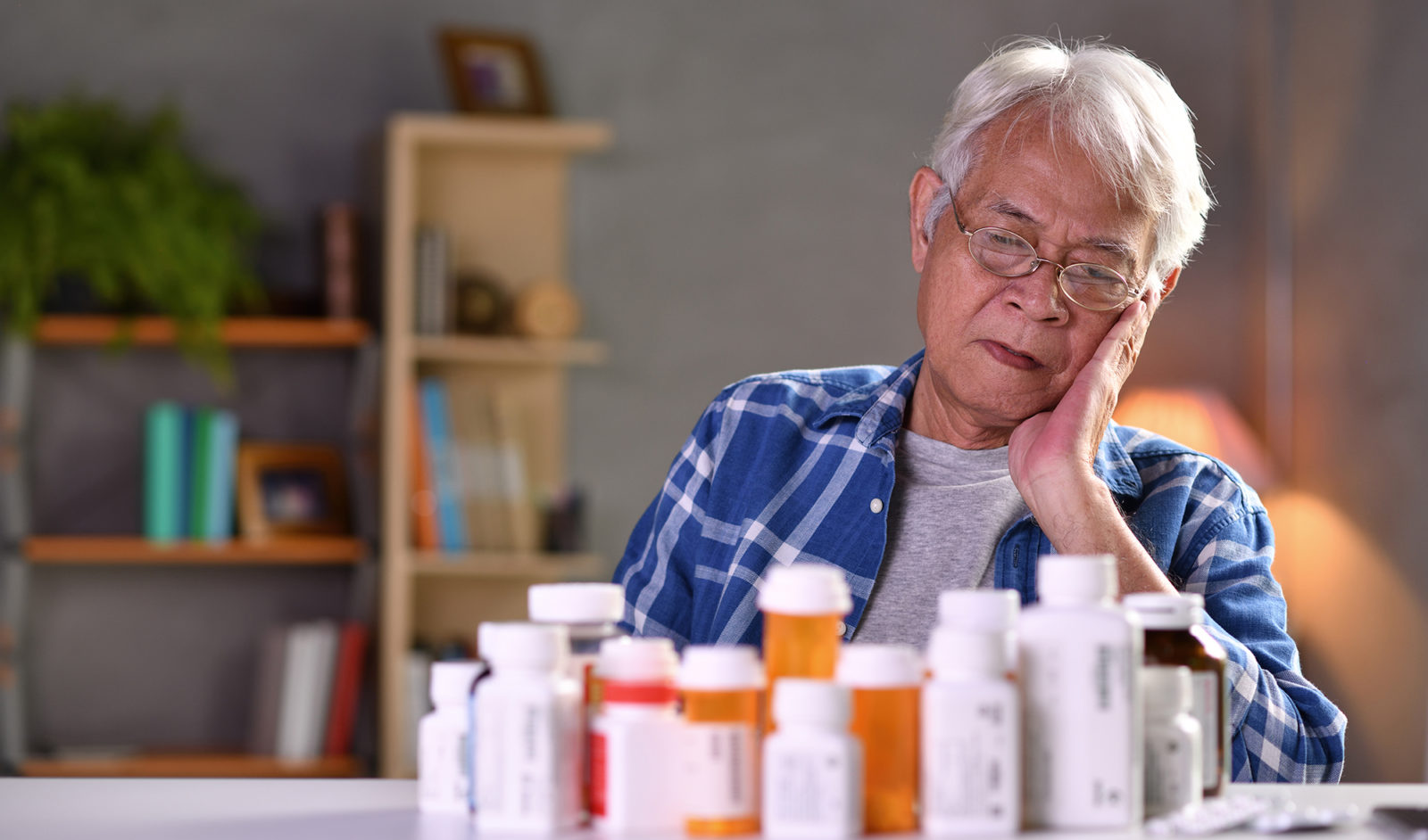 Older man with more than a dozen prescription medication bottles
