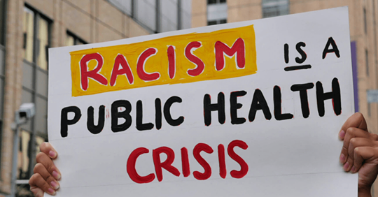 protest sign - racism is a public health crisis