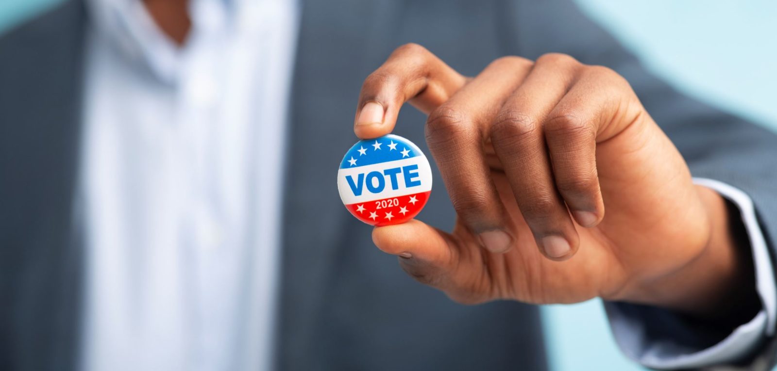 African American man holds a VOTE lapel button