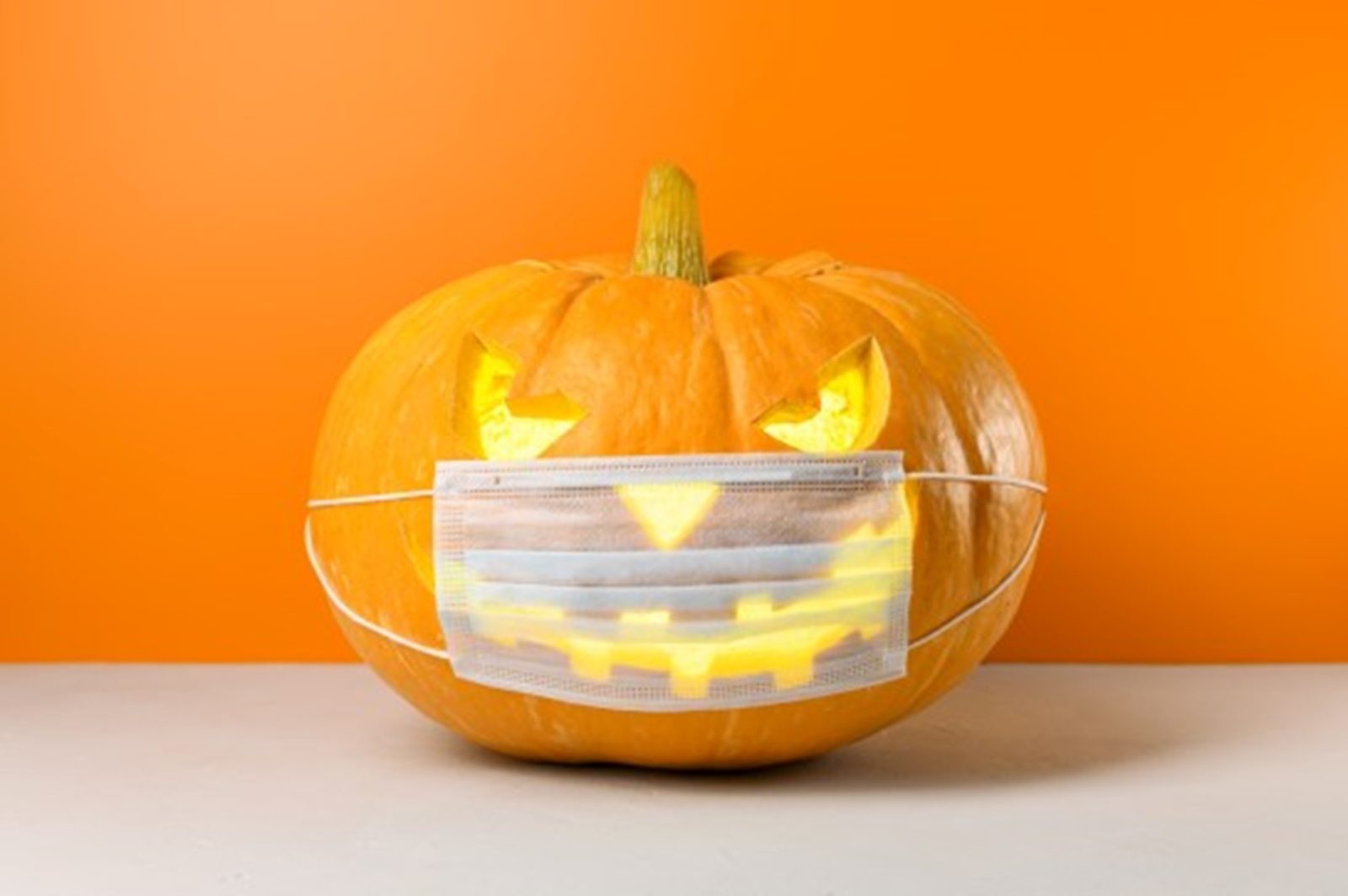 Halloween jack-o-lantern wears a face mask to prevent disease transmission