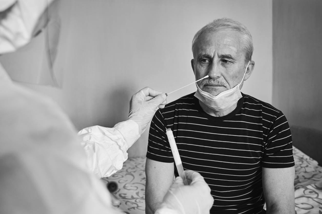 technician wearing Personal Protective geat uses a swab to administer a COVID test