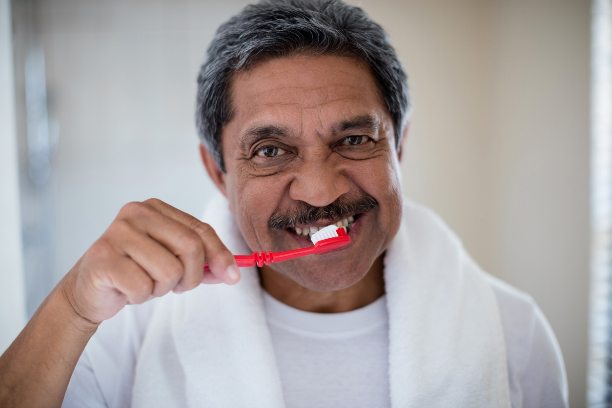 Older man brushing teeth in bathroom at home