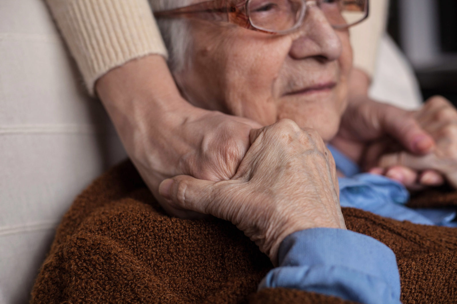 Older person with a loved one's hands on shoulders