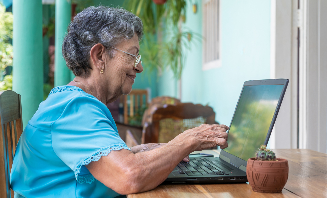 Smiling older woman wearing glasses with a laptop