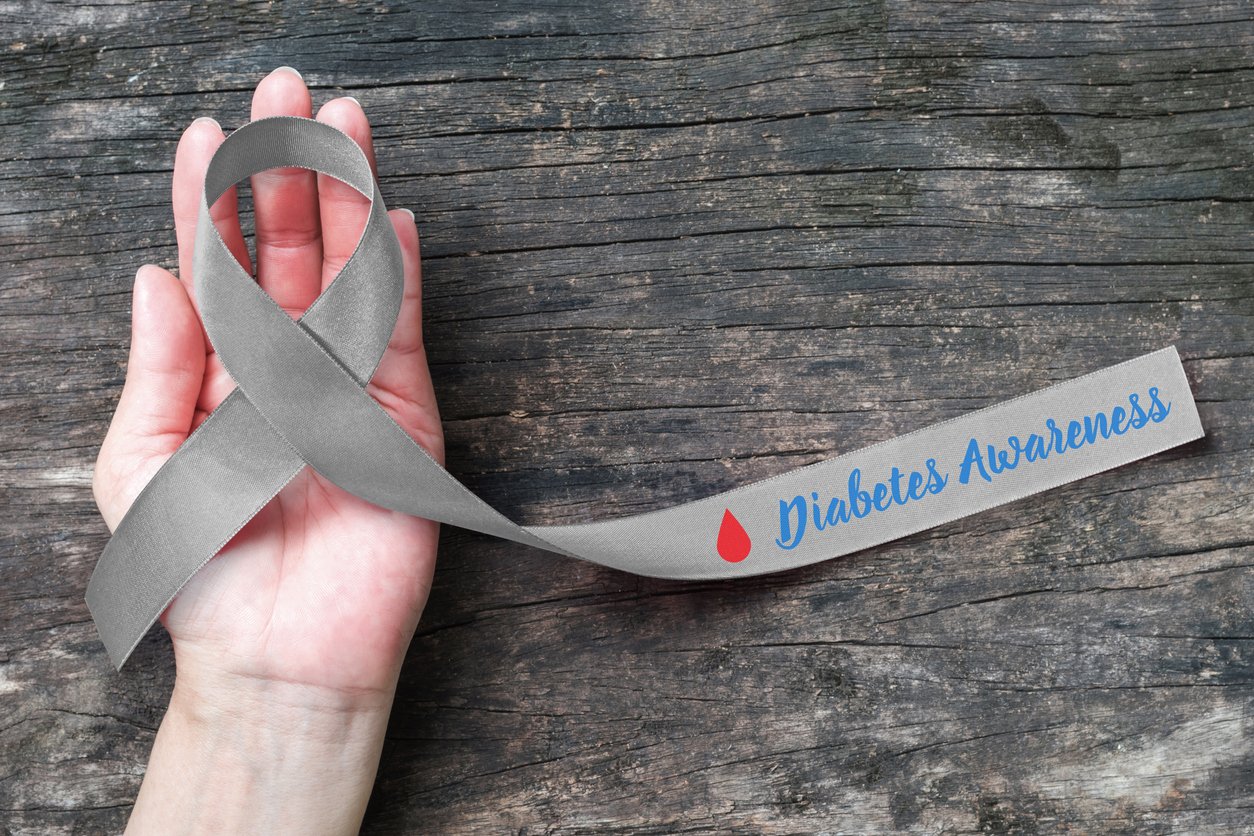 hand with open palm holding a Diabetes Awareness ribbon