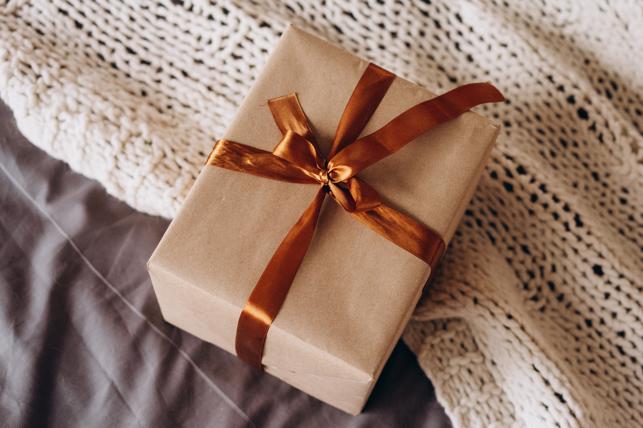 brown paper wrapped gift tied with a shiny copper-colored ribbon and bow