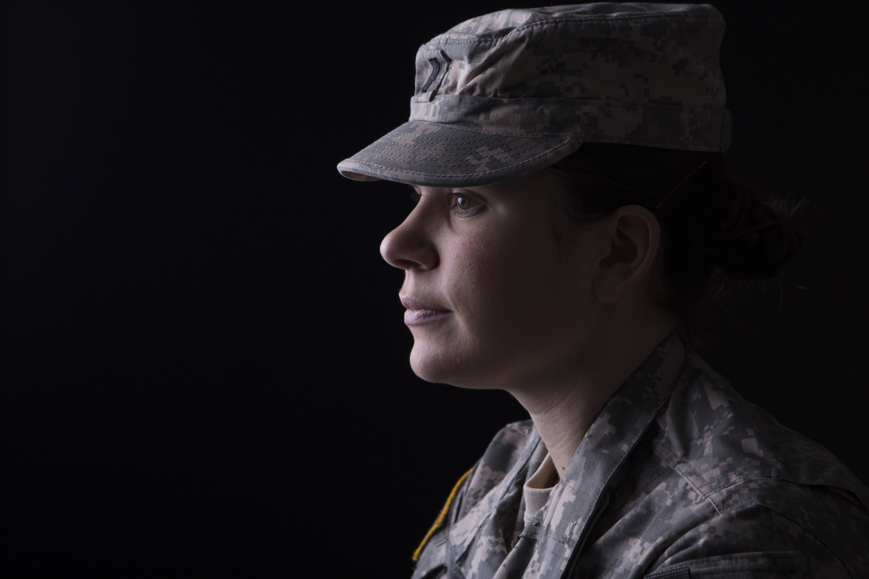 female member of the military wearing green fatigues shirt and cap