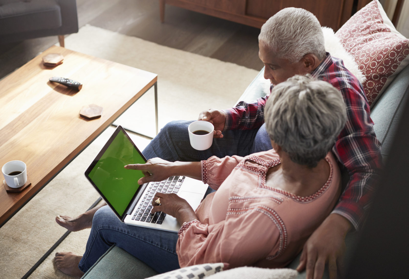 older woman and man sitting on a sofa with an open laptop, having a conversation