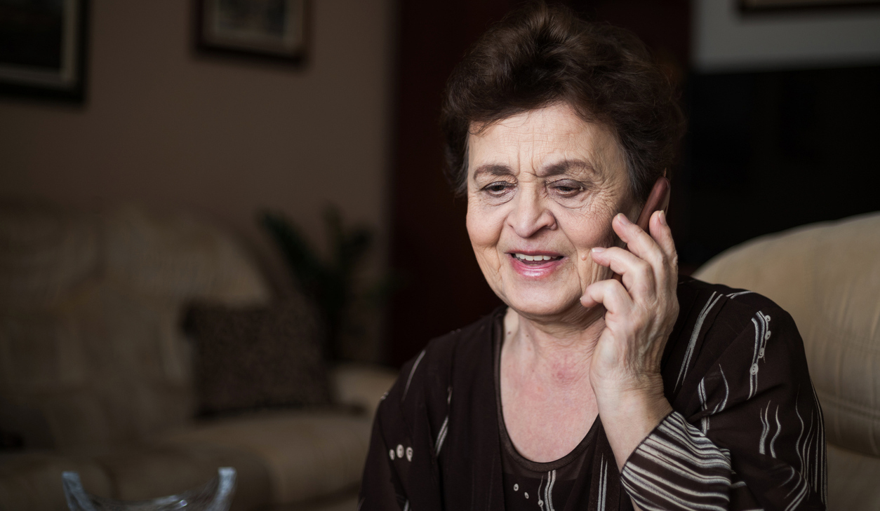 An older woman smiles as she talks on the phone