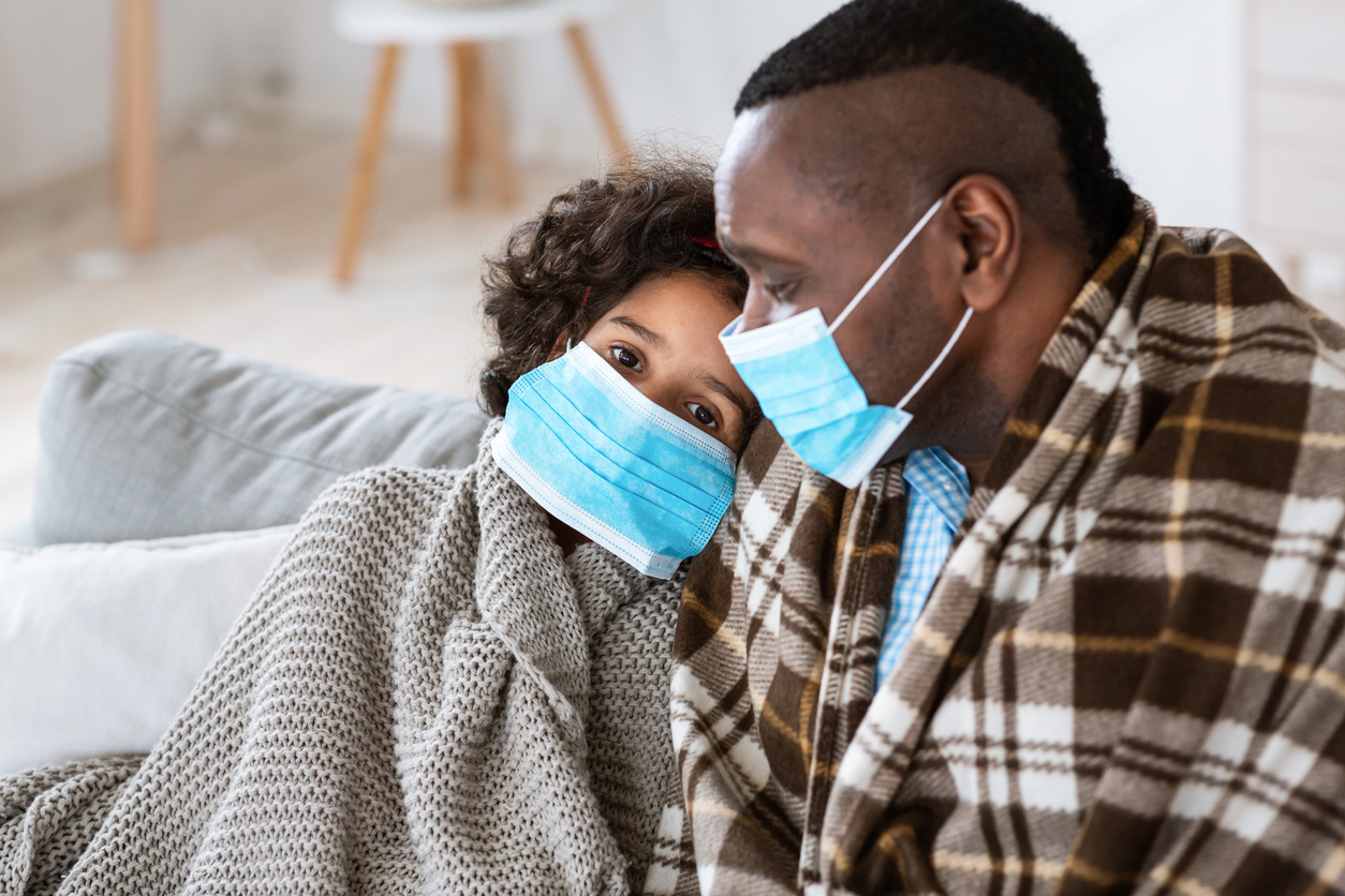 grandfather and child wearing medical masks at home, wrapped in a blanket