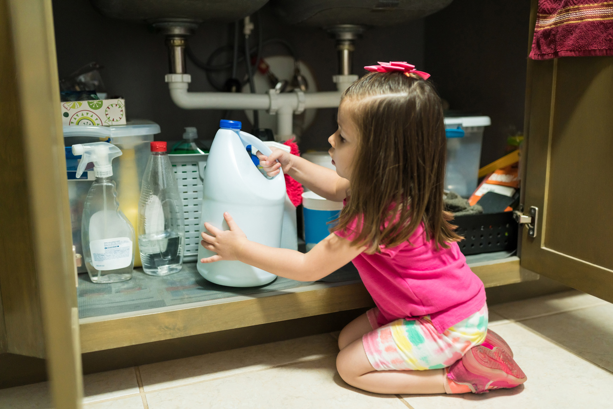 young child removing container from cabinet in kitchen at home