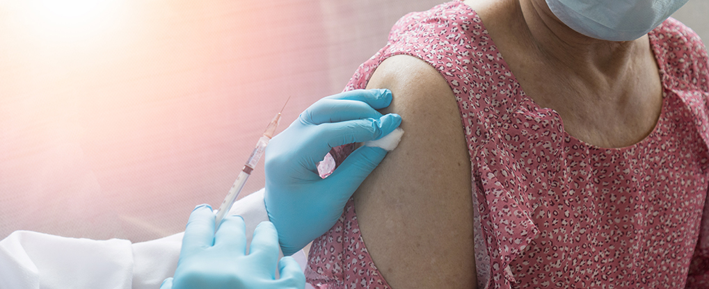 Covid-19 vaccine concept. Hand of doctor in medical gloves with syringe and vaccination for vulnerable group old people in hospital for new coronavirus disease