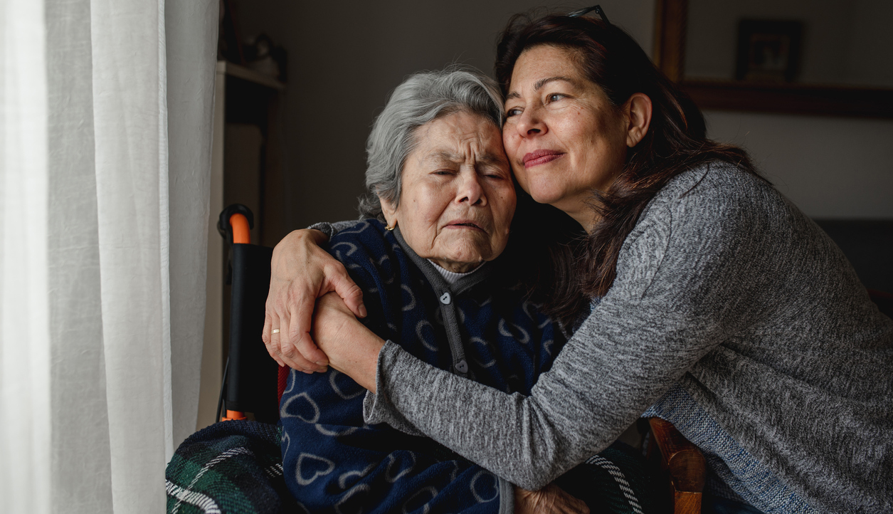 woman in wheelchair hugging daughter with positive face. Home care concept.