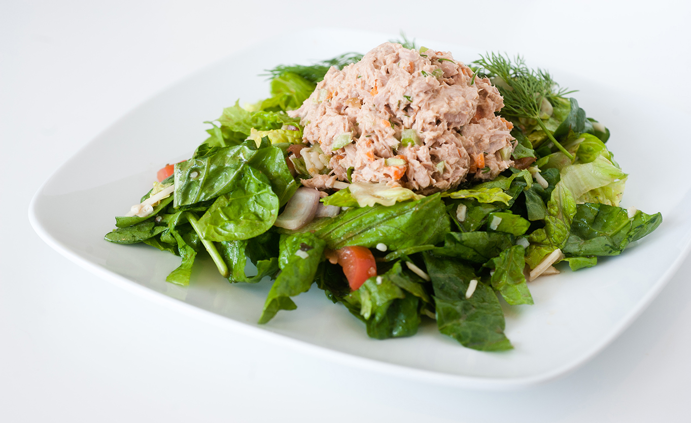 a scoop of tuna salad on top of lettuce and tomatoes
