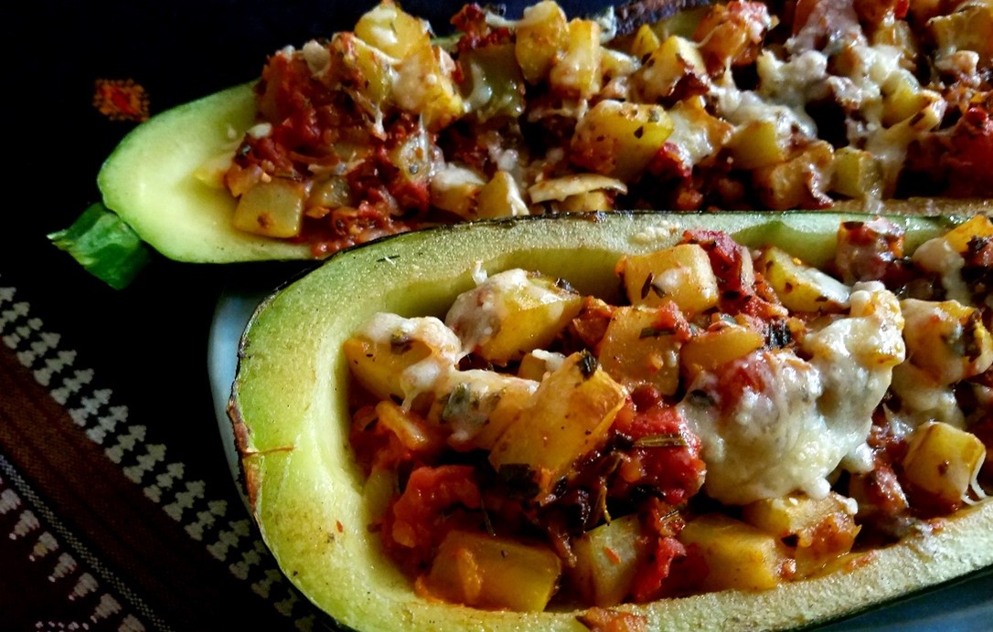 two zucchini halves stuffed with vegetables and cheese, just out of the oven