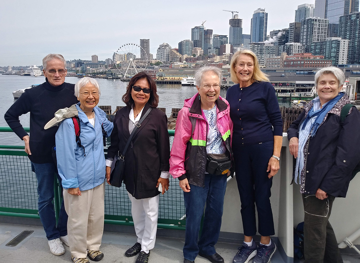 6 people affiliated with the Greenwood Senior Center in northwest Seattle, standing on a pier or a ferry boat on Seattle's waterfront