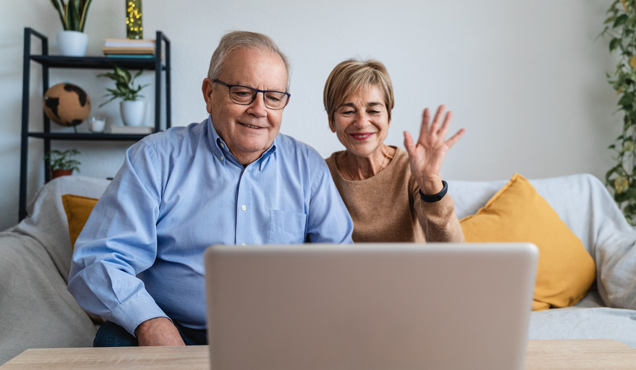 Happy older couple having video call using laptop computer at home