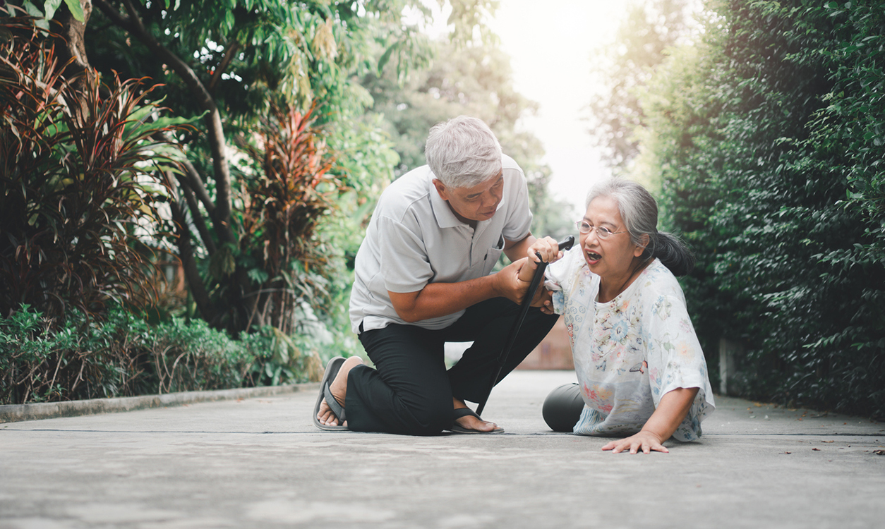 Older Asian man helping an older Asian woman up from the ground