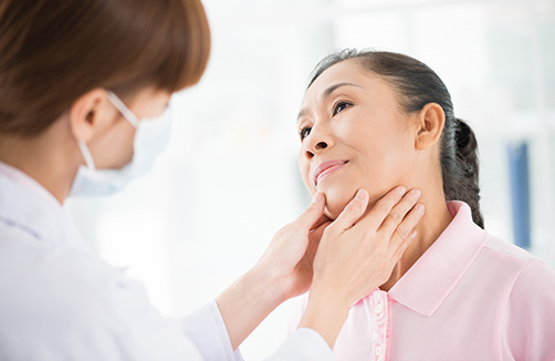health care provider feels glands in neck of an older Asian woman