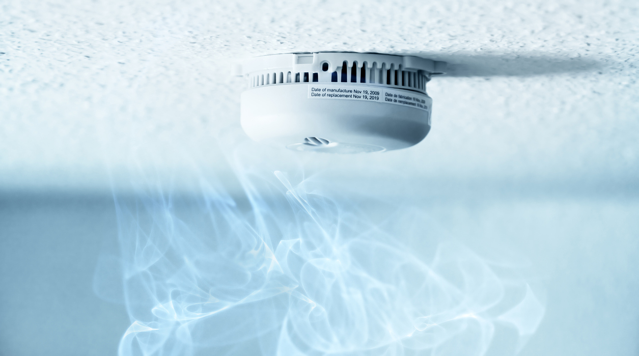 A smoke detector installed at a ceiling with smoke.