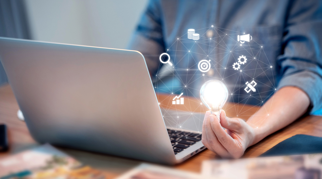 Woman at laptop computer with hand holding illuminated light bulb, idea concept.