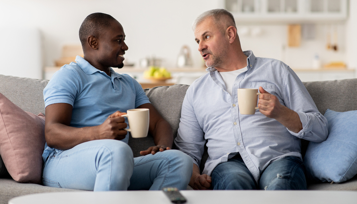 two men enjoy a conversation over coffee, sitting on a couch