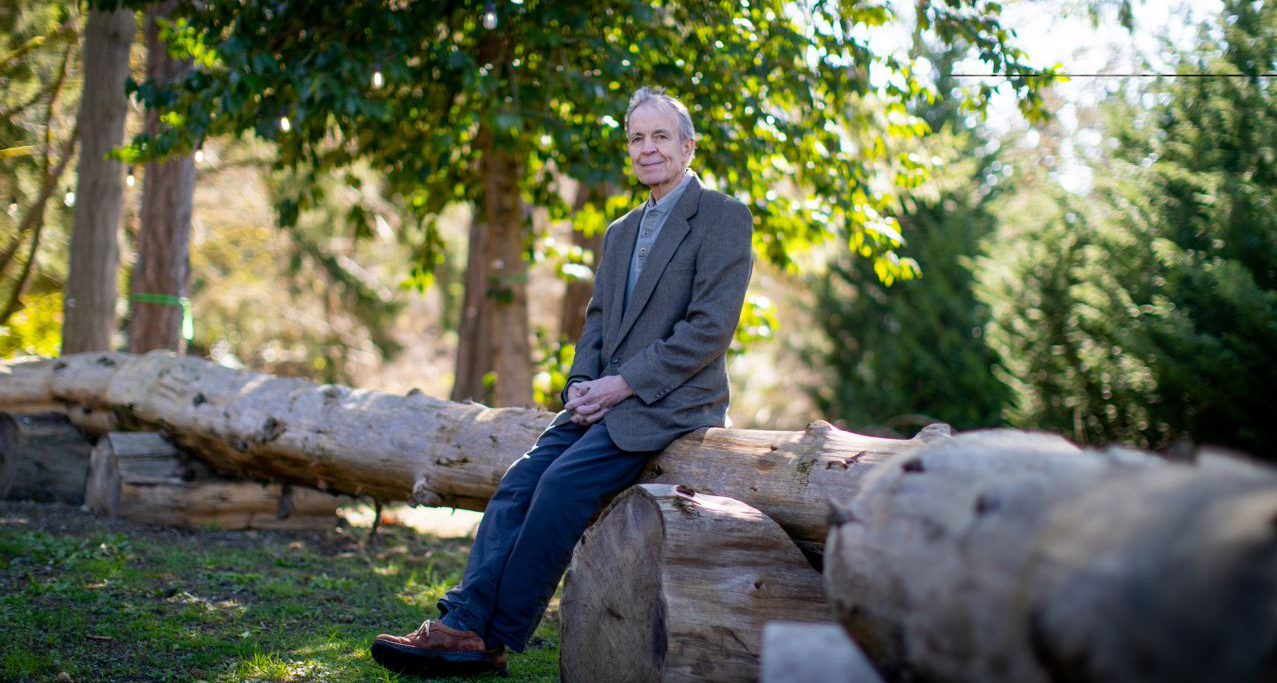 Jim Copen, wearing slacks and a sports coat, looking healthy as he leans against a tree in a park setting