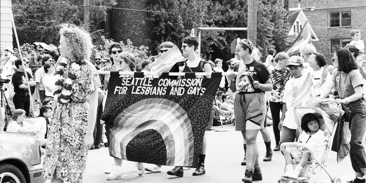 historical photo of Gay Pride March - participants carry a Seattle Commission for Lesbians and Gays banner
