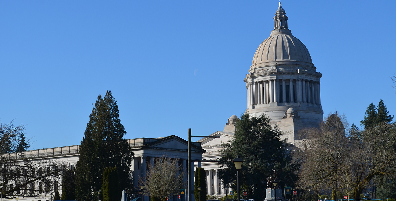 state capitol dome and other buildings with a bright blue winter sky