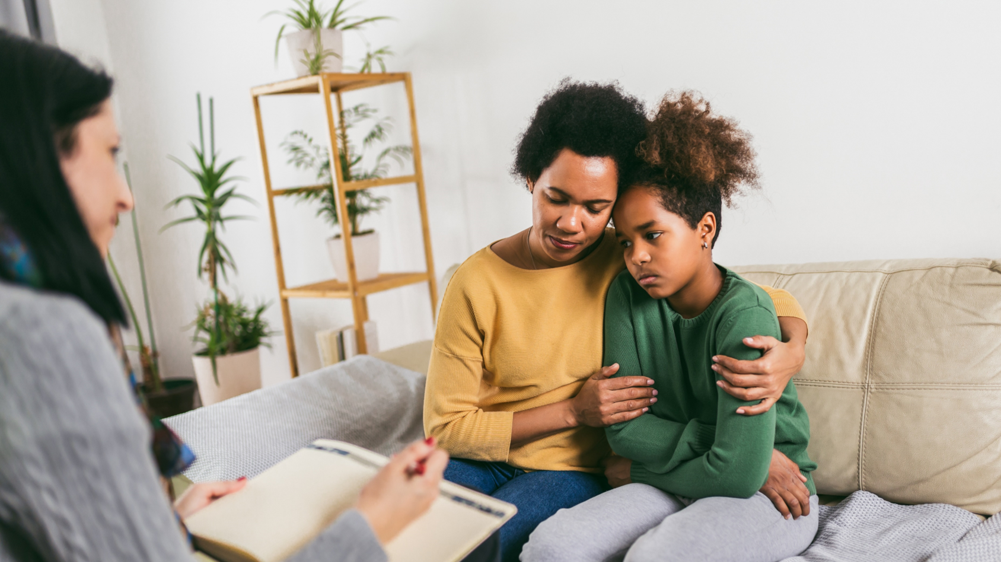 a victim support advocate talks with two people who are hugging themselves in support of one another