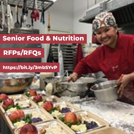 smiling cook wearing a red chef's coat and head scarf, preparing meals in mass - Senior Food/Nutrition RFPs/RFQs - https://bit.ly/3mbSYvP