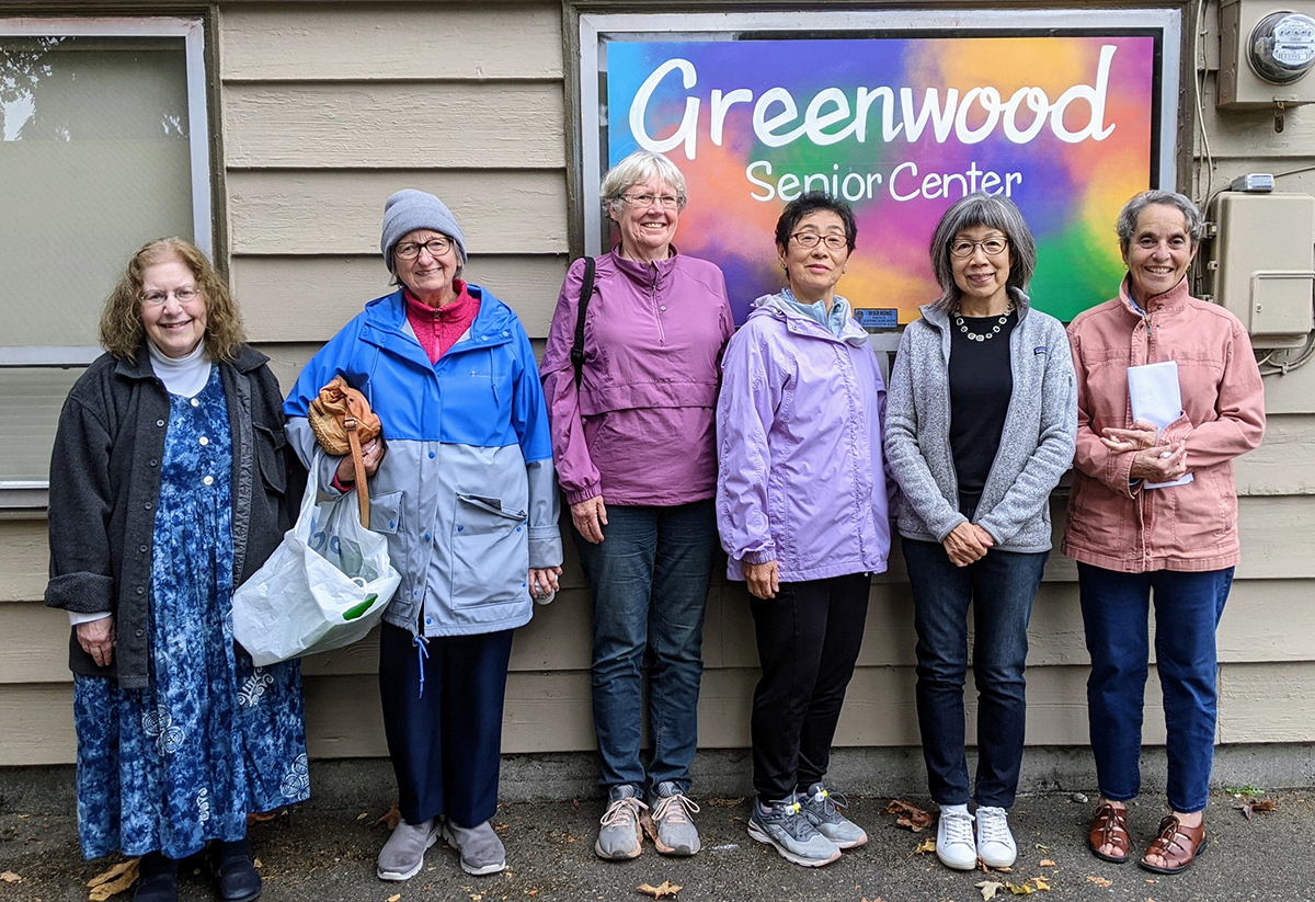 Greenwood Senior Center participants standing outdoors in front of a senior center banner