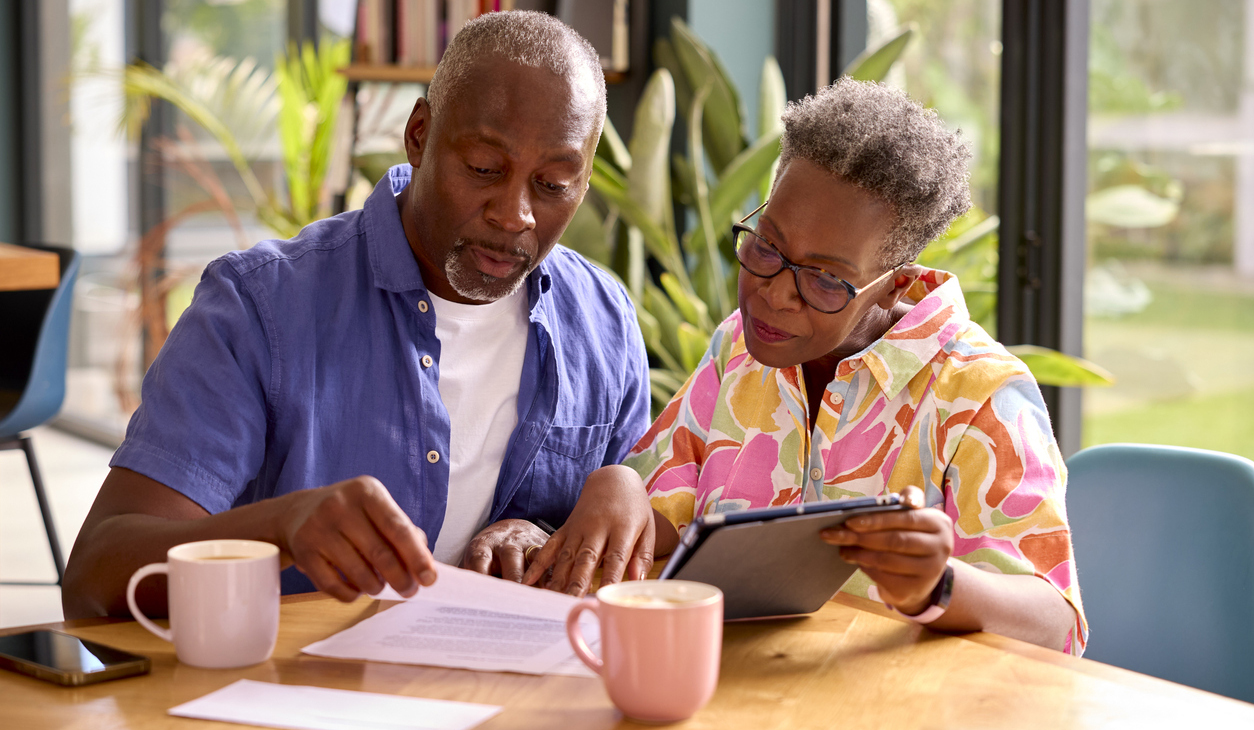 Older Couple Sitting at Table At Home Reviewing Finances
