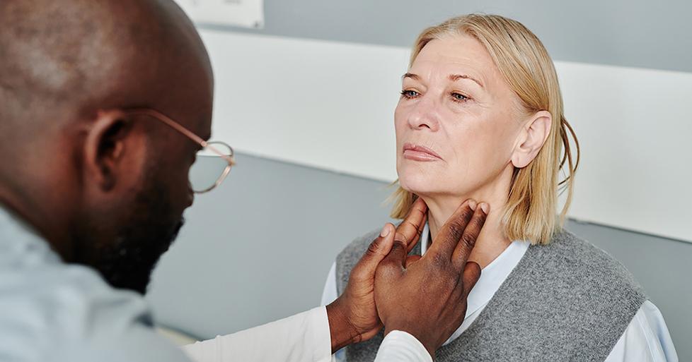 male doctor checking woman's thyroid